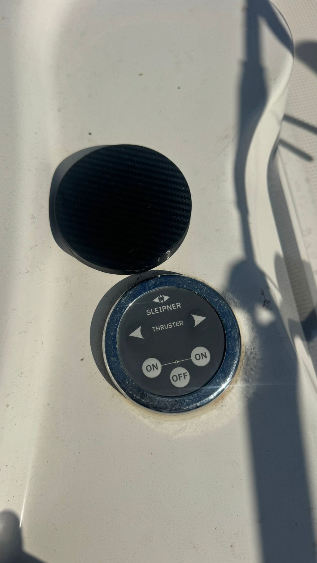 Control panel with a black knob and circular switch on a white surface.